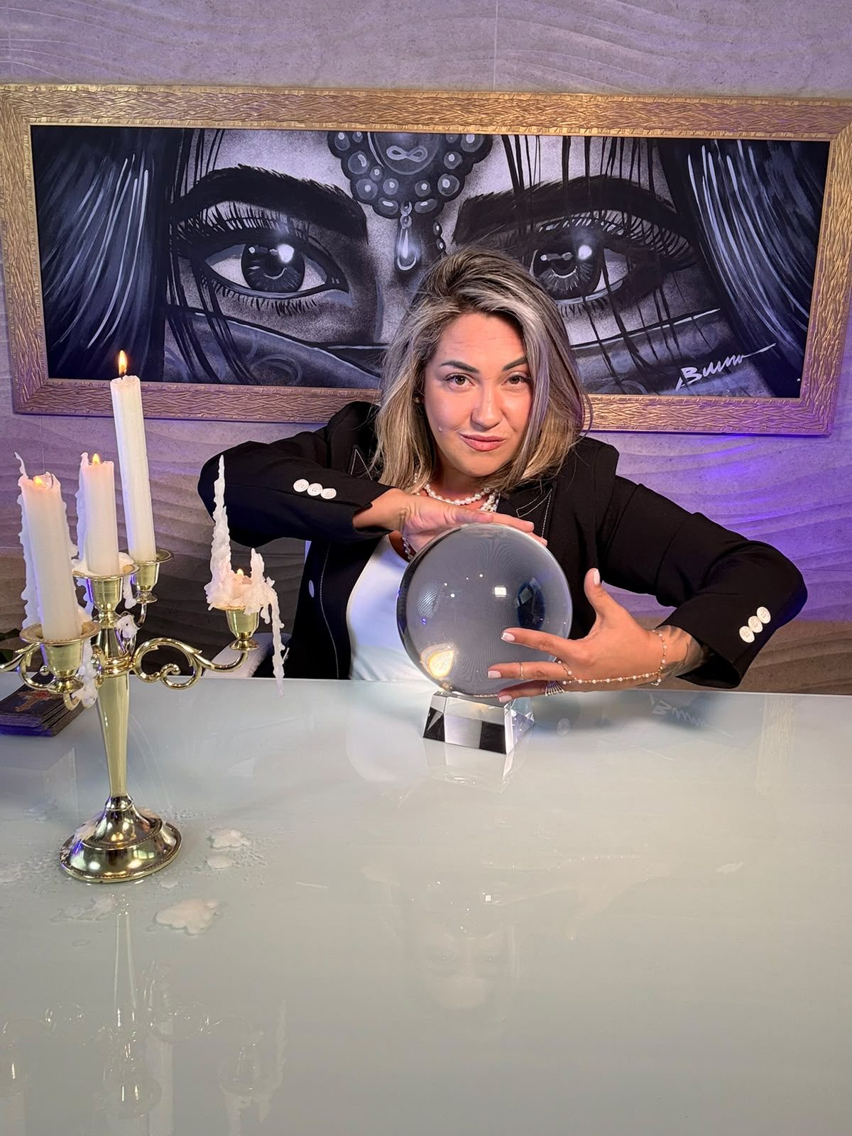 Mariah Sayão à mesa de atendimento com a bola de cristal